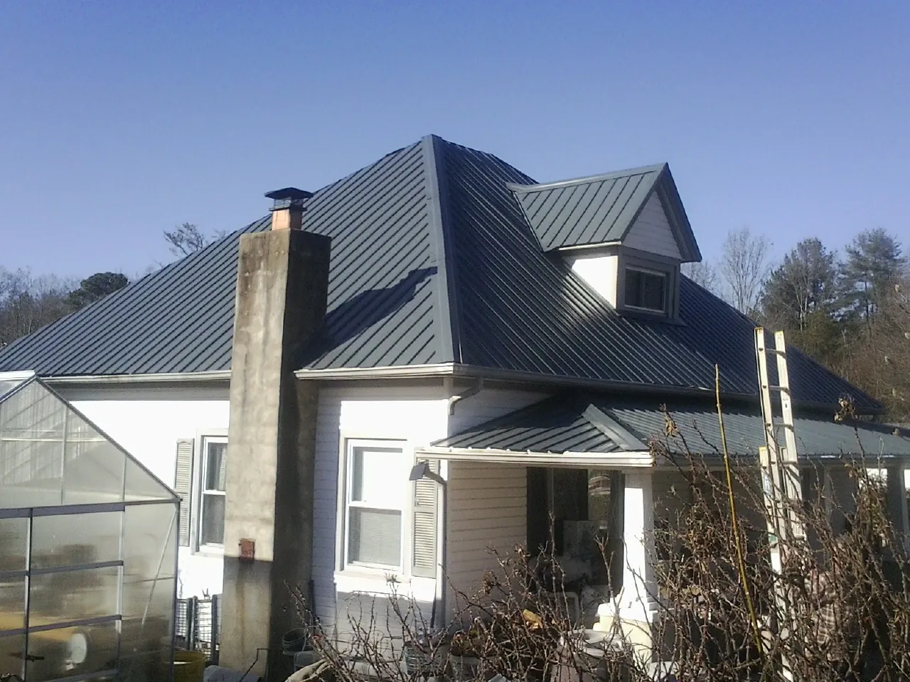 Dark blue standing seam metal roof on a white farmhouse with dormer — Slate & Tile Roof Repair by Roofing Brothers in Kimberly