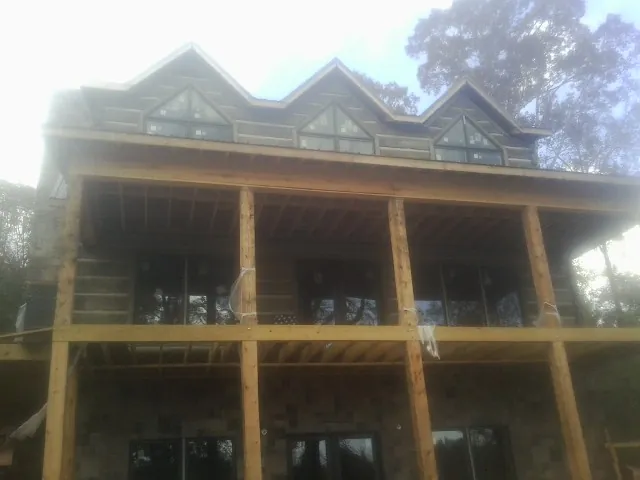 Dormers and porch framing on a large log home under construction — Roof Coating work by our crew in Kimberly