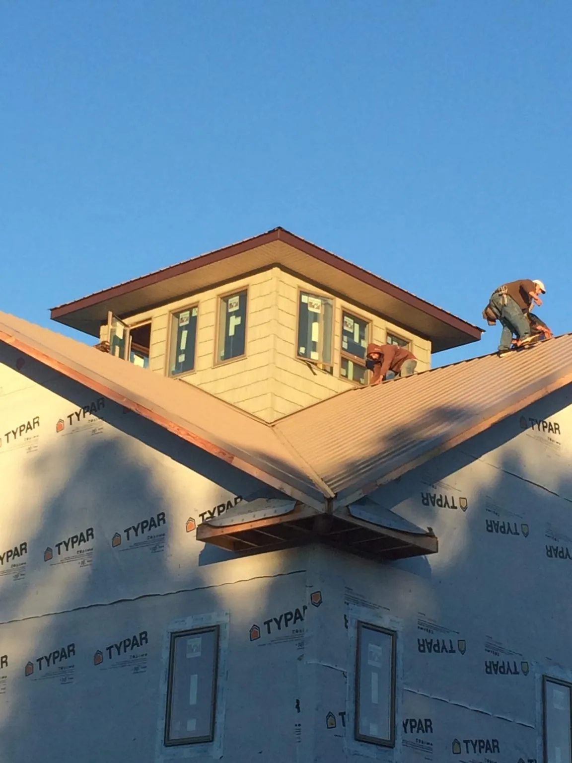 Roofers working around a rooftop cupola on a new metal roof at sunset — Roof Waterproofing in Kimberly by Roofing Brothers